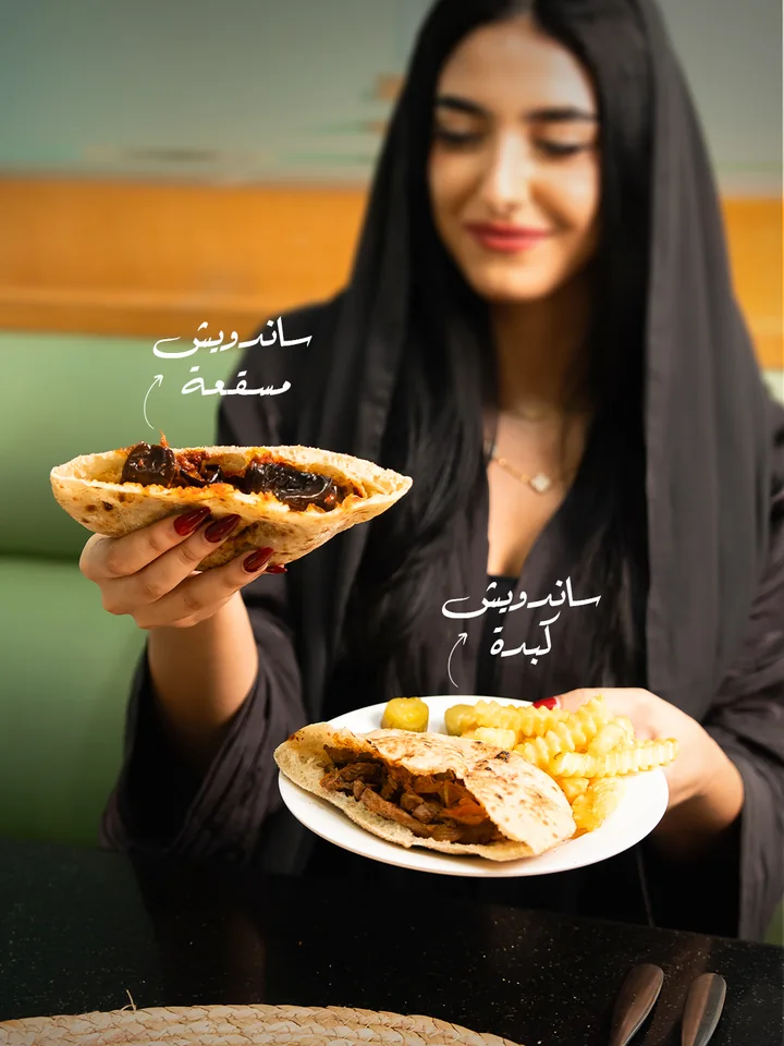 Guest holding a sandwich and a plate of food